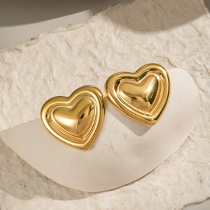 Macro view of polished gold heart stud earrings with smooth metallic finish