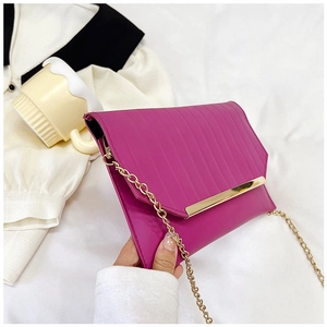 Close-up of rose red envelope evening clutch with gold chain and metal trim