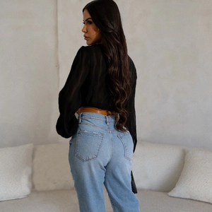 Back view of a black pleated long sleeve cardigan with a belted waist and jeans