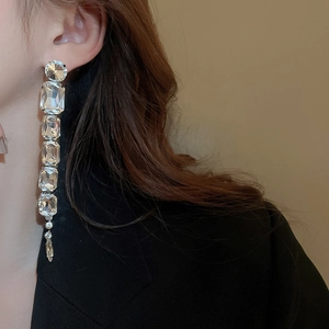Close-up of silver tassel earrings with geometric crystals worn by a model