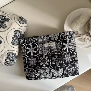 Detail of elegant black canvas makeup bag featuring intricate white floral embroidery