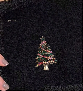 Detailed view of a sparkling Christmas tree brooch with colorful rhinestones on black tweed