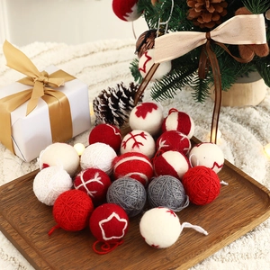 Knitted wool Christmas ball set with red, white, and gray embroidery on a wooden tray
