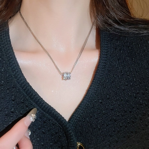 Close-up of a silver multilayered zircon cylinder pendant necklace on a model