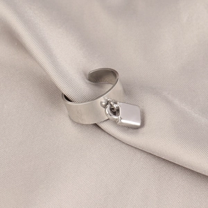 Macro shot of polished silver padlock pendant on wide stainless steel open ring