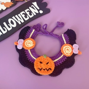 Detail van handgemaakte Halloween huisdier halsband met pompoenen op paars gebreid garen