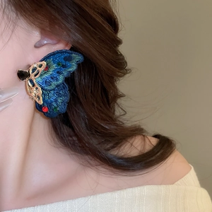 Detailed close-up of peacock blue embroidered butterfly earring with crystal accents