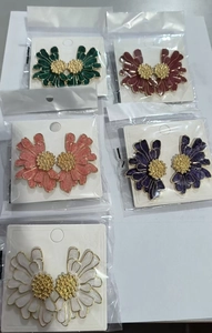 Detail view of colorful daisy floral stud earrings in five colors in individual packaging