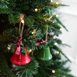 Red and green Christmas iron bells with pine needles and bow on a festive tree