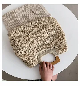 Detail of hand-woven straw tote bag with integrated semicircular wooden handle for beach