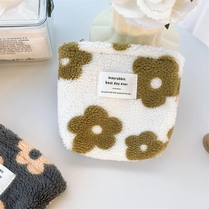 Close-up of white plush coin purse with green floral pattern and mayrabbit text logo