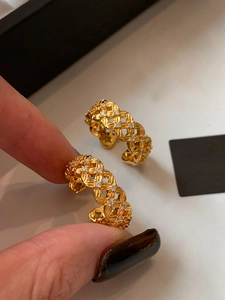 Detailed view of gold-plated hollow braided earrings with inlaid zircon on hand