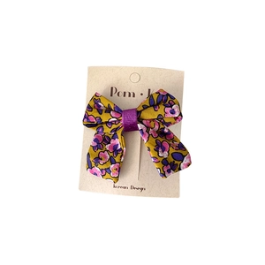 Floral fabric bow hair clip in yellow and purple on display card for girls
