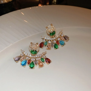 Macro shot of leopard head stud earrings with colorful zircon tassels on ceramic plate