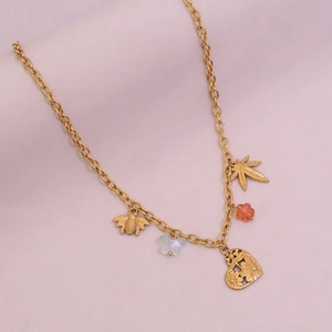 Détail du collier doré avec pendentifs abeille, papillon, fleur et cœur évidé