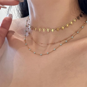 Detail of layered gold heart choker necklace with pink and cyan beaded accent chains