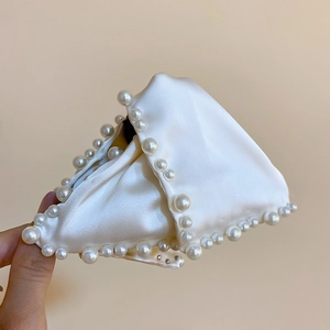 Gros plan d'une pince à cheveux élégante en satin blanc avec détails de perles nacrées