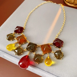 Dettaglio della collana con pendenti in resina ambrata e rosso-bruno su catena d'oro