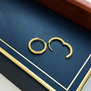 Elegant gold twisted hoop earrings with easy-click closure on luxury jewelry box