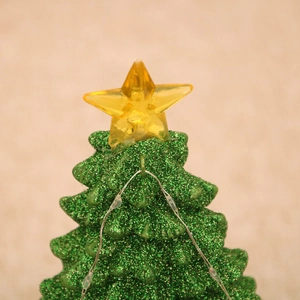 Close-up of a resin Christmas tree music box featuring LED lights and a golden star topper