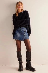 Détail d'une mini-jupe en denim bleu à ourlet irrégulier avec ceinture à boucle métallique