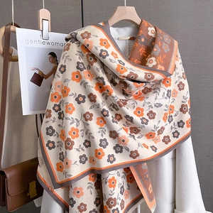 Detailed texture of a floral vintage scarf with warm beige and orange flower patterns