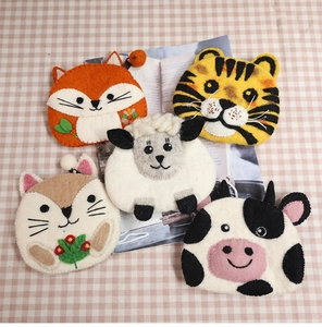 Detailed flat lay of five handmade wool felt animal coin purses on a pink plaid tablecloth