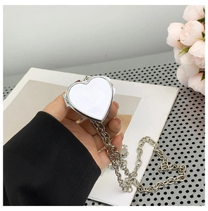 Detailed macro shot of a heart-shaped silver metal mirror pendant and chunky chain
