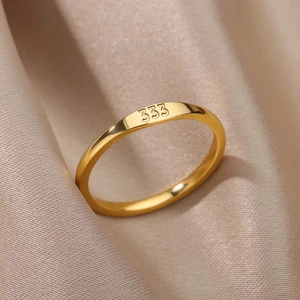 Macro shot of gold-plated stainless steel ring with 333 engraving on champagne silk