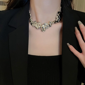Detailed close-up of irregular silver lava-style metal necklace worn by a model