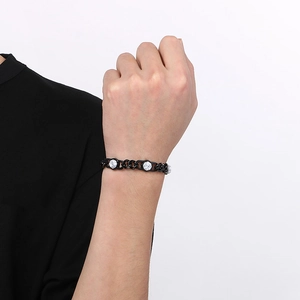 Detail of a gold Cuban link bracelet with marble-textured stones worn on a wrist