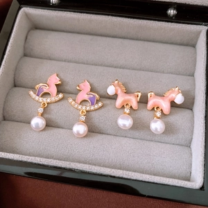 Dettaglio degli orecchini a forma di pony placcati oro 18K con smalto e perle su velluto