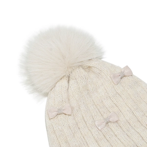 Detail of knit hat texture with pink satin bows and fluffy faux fur pom-pom topper