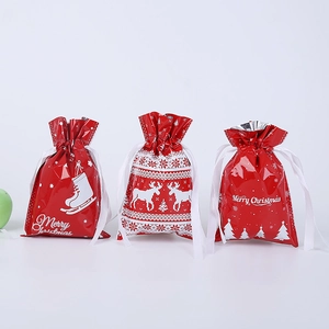 Three Christmas drawstring gift bags with reindeer and tree patterns on white background