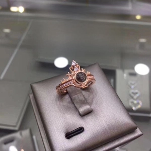 Detail of rose gold crown ring featuring a 100 languages projection stone on a display
