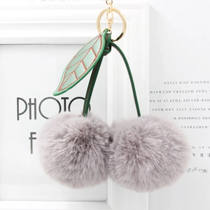 Detailed view of gray faux fur cherry keychain with green leather leaves and gold hardware