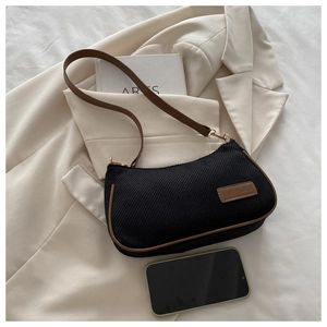 Black canvas and brown leather underarm bag styled with a blazer and lifestyle accessories