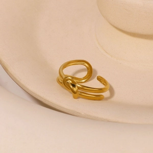 Minimalistischer goldener Knotenring mit verstellbarem Band auf beigem Teller