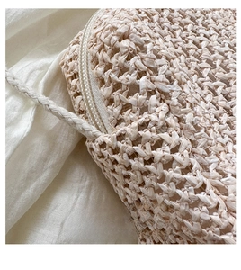 Detail of hand-woven straw bag showing geometric texture and zipper closure