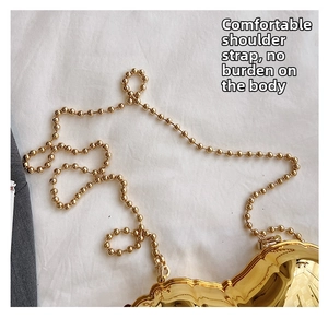 Macro view of metallic gold heart-shaped mini bag featuring a beaded chain strap