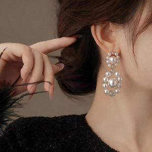 Macro detail of elegant pearl drop earrings with sparkling cubic zirconia on a model