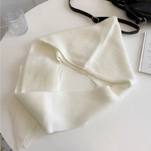 Detailed view of soft white knitted scarf texture on a minimalist desk layout