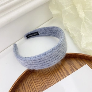 Detailed close-up of light blue knitted plush headband with a Hand Made label