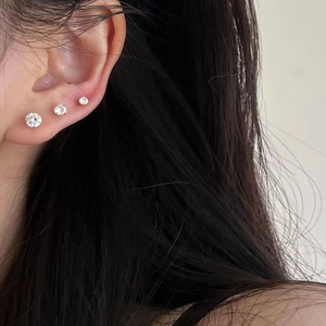 Three gold-plated 925 silver stud earrings with clear zircon stones on a model's ear