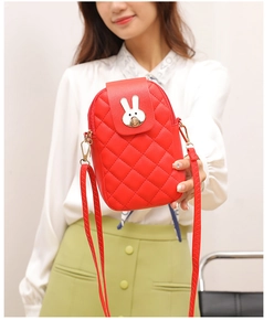 Detail of red quilted mini crossbody phone bag with metal rabbit buckle on woman's hand
