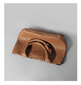 Detailed view of brown woven tote bag showing intricate handmade texture and handle