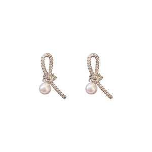 Boucles d'oreilles nœud argentées avec zircons et perle blanche sur fond blanc pur
