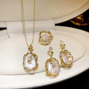Détails d'une parure de bijoux fleur dorée avec perles baroques et cristaux en boîte