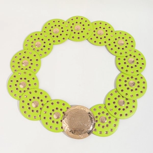 Detailed view of lime green leather disc belt with ornate floral gold buckle on white back