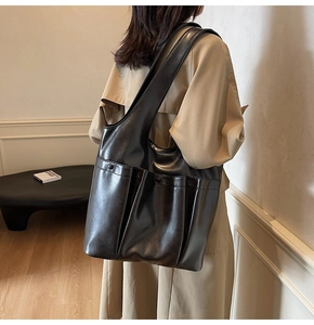 Detailed back view of a black oversized tote bag with external pockets on a model